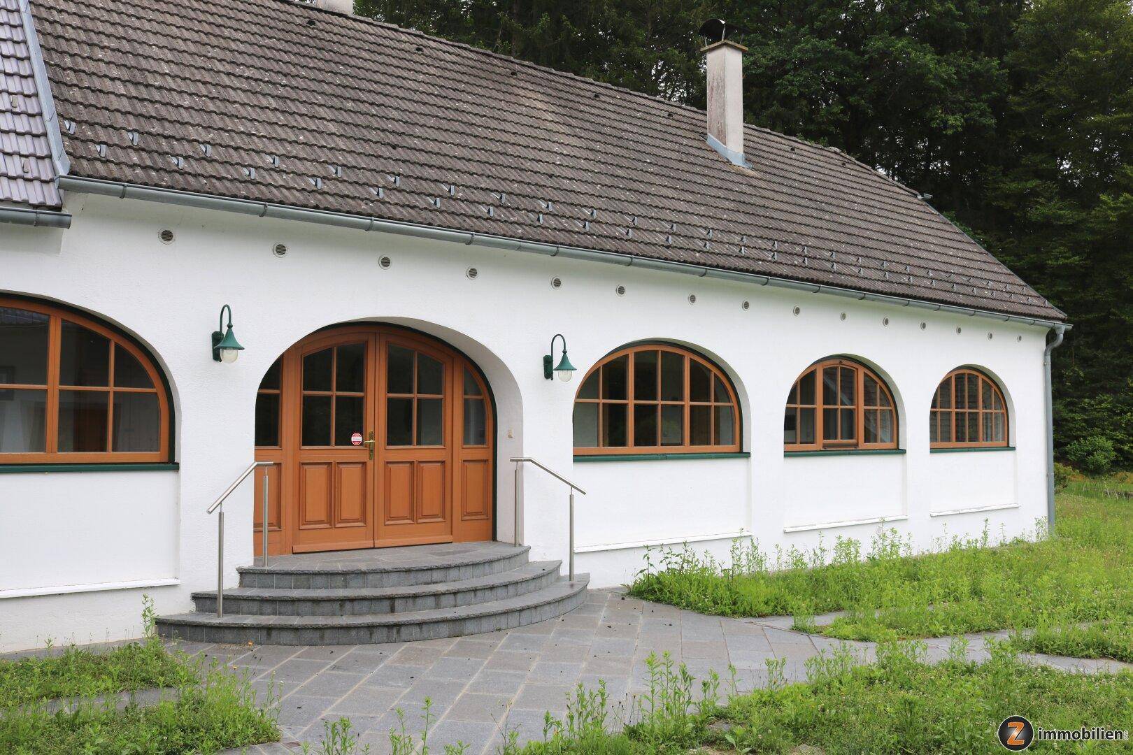 Haupteingang des Gebäudes mit Rundbogentüren und Steintreppe.