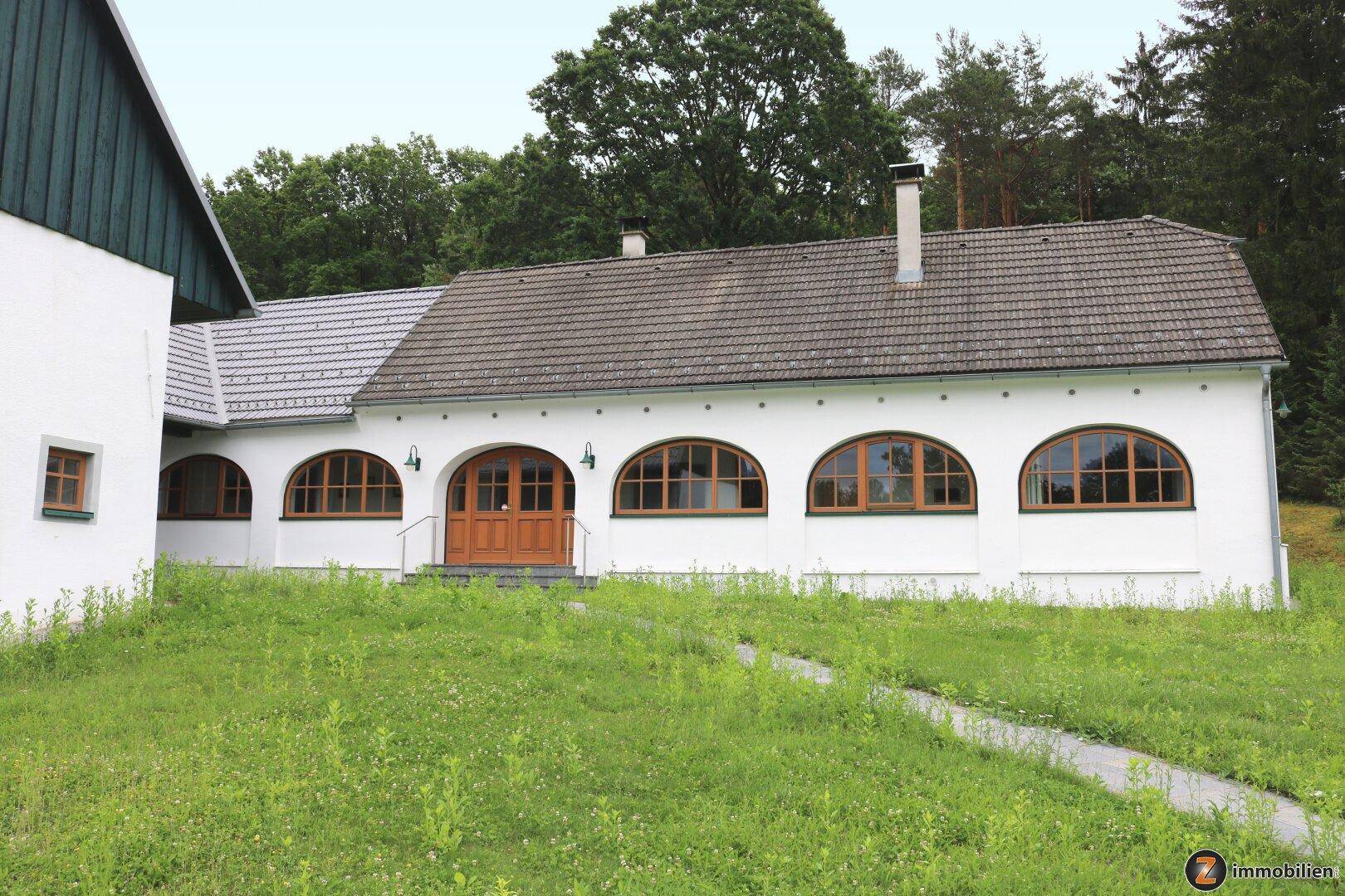 Ansicht der Gebäudefassade mit Rundbogenfenstern und gepflegter Grünfläche.