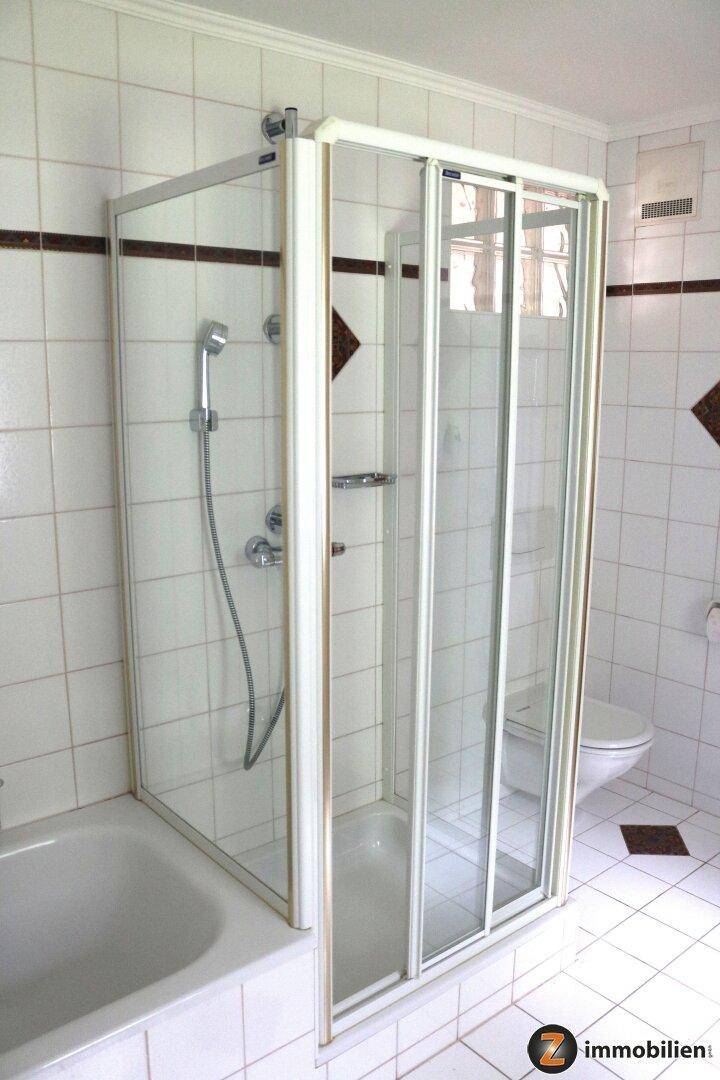 Duschbereich im Badezimmer mit Glasabtrennung und weißen Wandfliesen.