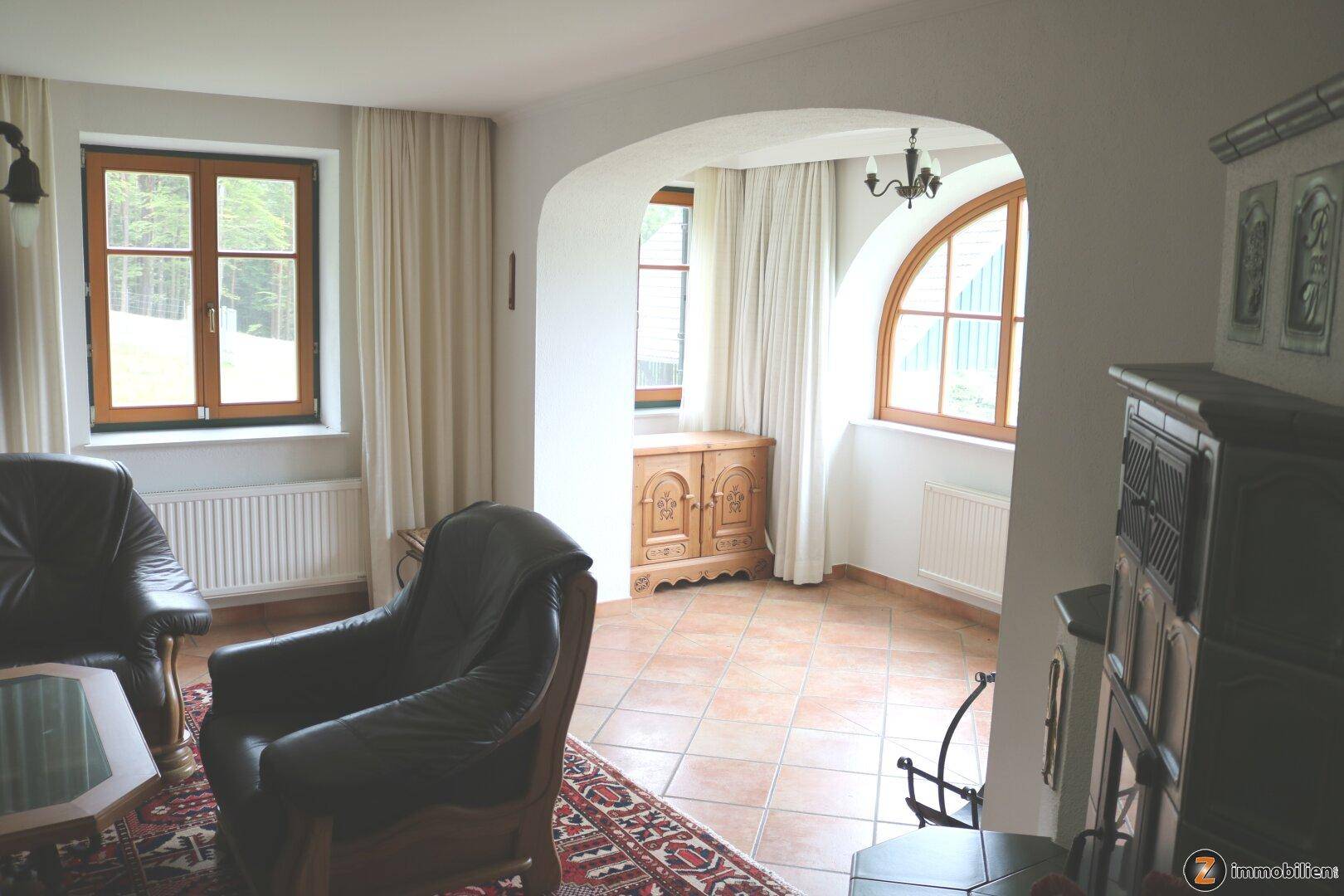 Wohnzimmer mit Terrakottafliesen, Rundbogenfenstern und Blick ins Grüne.