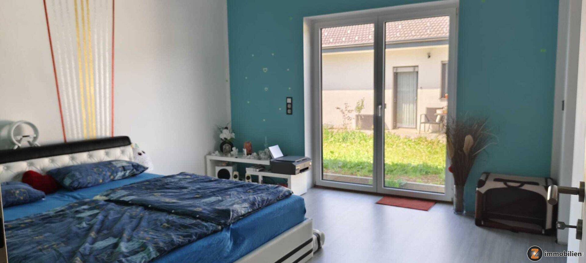 Helles Schlafzimmer mit farbiger Wandgestaltung und direktem Zugang zum Garten.