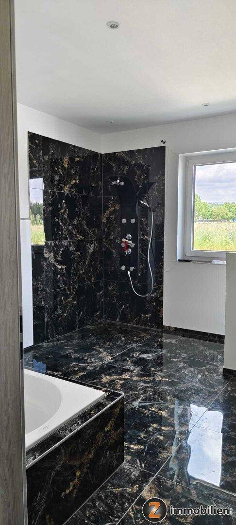 Geräumiges Badezimmer mit großer begehbarer Dusche und Fenster mit Weitblick.