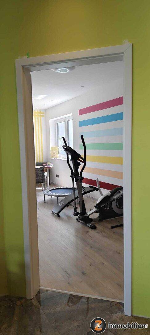 Raum mit Fitnessgeräten und farbenfroher Wandgestaltung, ideal für Sport.