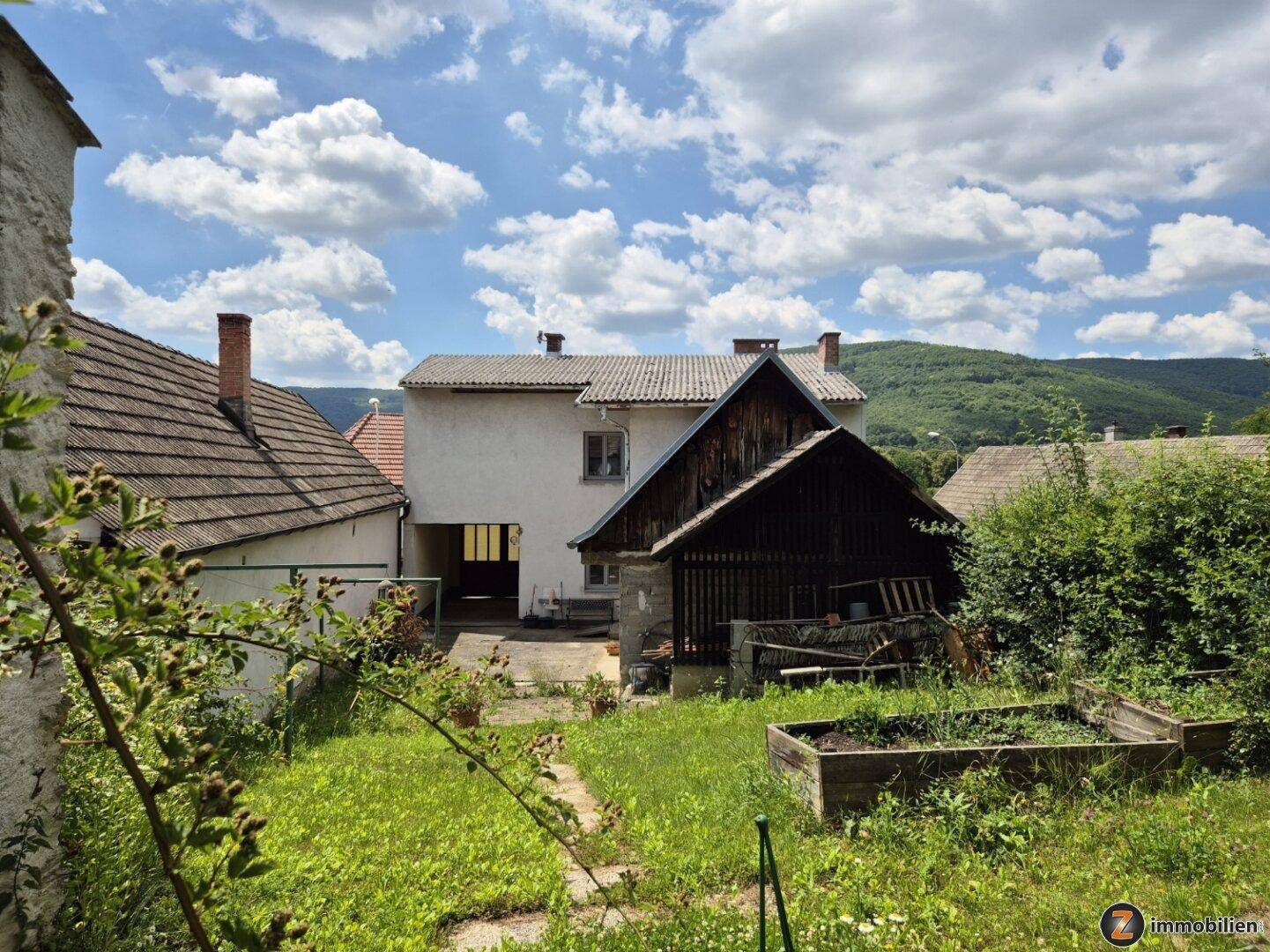 Hinteransicht des Hauses mit Garten, Nebengebäuden und Blick auf die umliegende Landschaft.