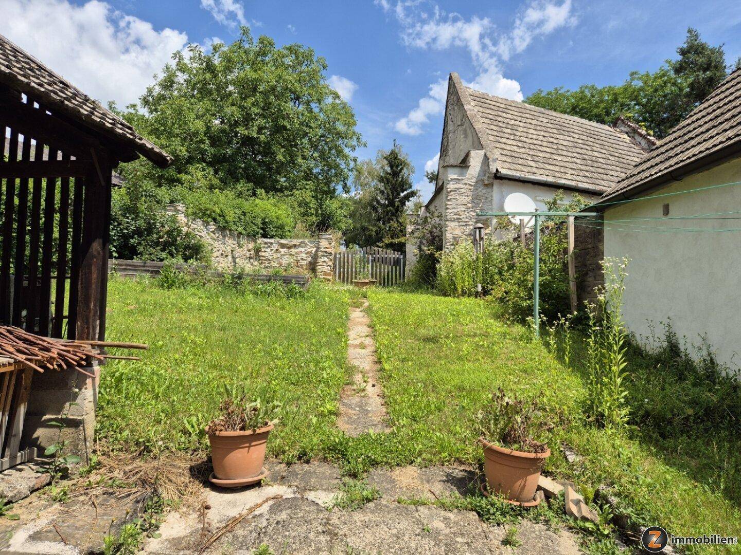 Großer, naturbelassener Gartenbereich mit alten Mauern und Blick auf weitere Gebäude.