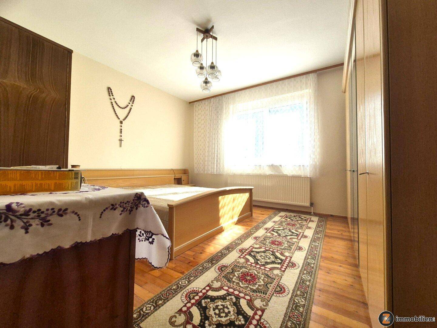 Gemütliches Schlafzimmer mit Holzbett, Kleiderschrank und Teppichläufer.