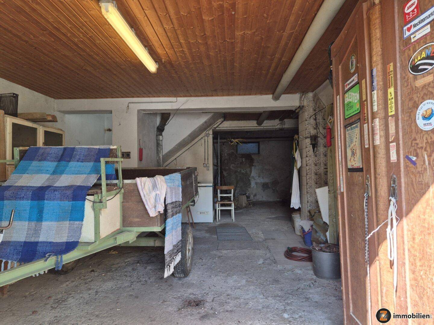 Geräumige Garage mit Holzbalkendecke und Platz für Fahrzeuge und Lagerung.