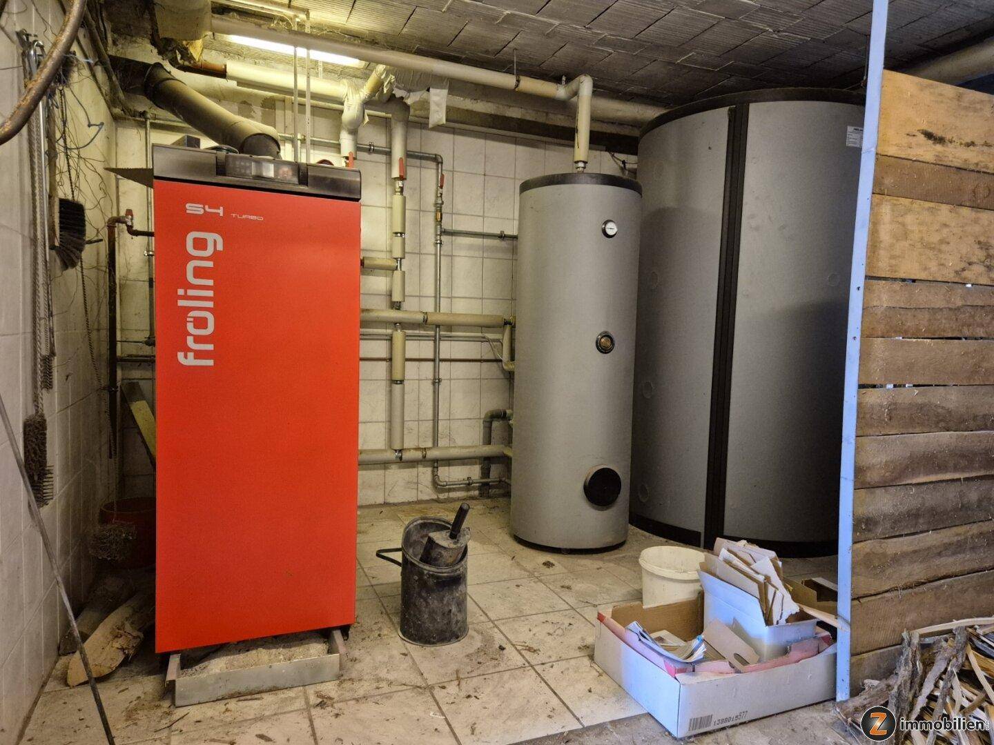 Heizungsraum mit modernem Holzvergaserofen und Warmwasserspeichern.