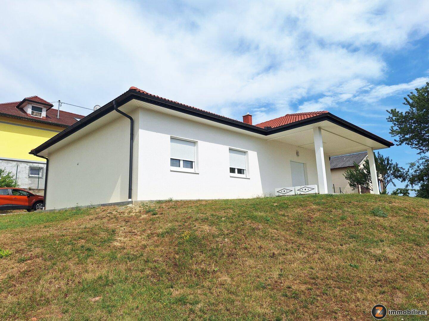 Ansicht des modernen Einfamilienhauses mit weißer Fassade und rotem Dach.