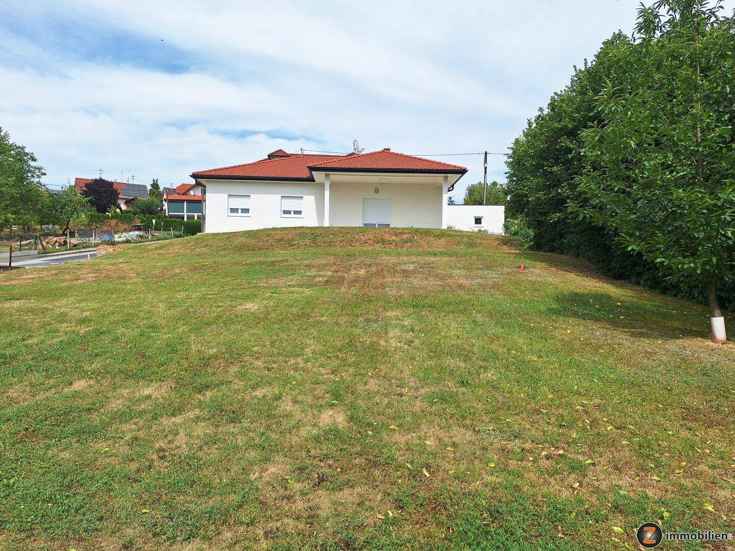 Freistehendes Einfamilienhaus auf einem grünen Hügel mit weitem Blick.