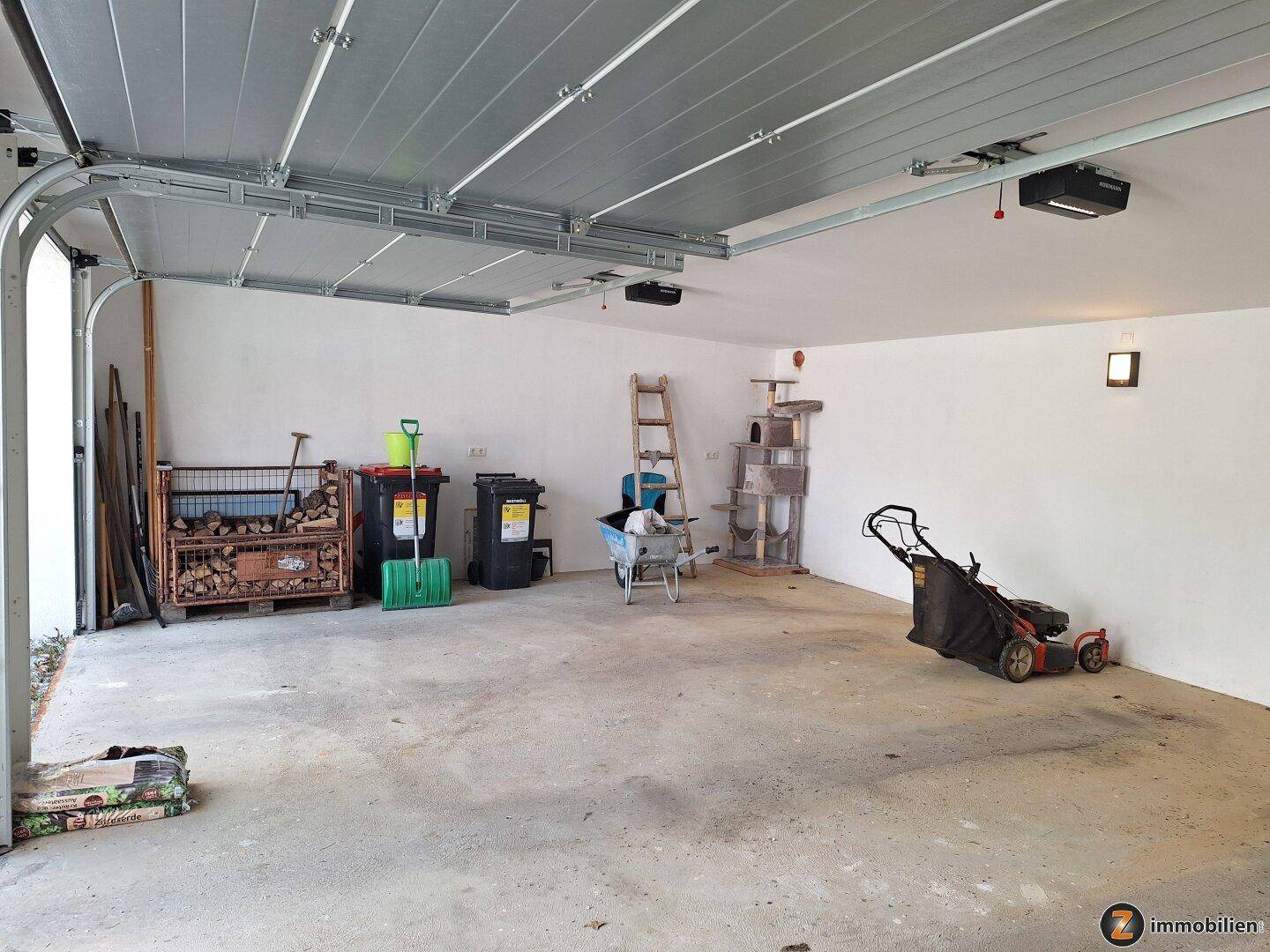 Geräumige Garage mit Betonboden, Lagerfläche und Gartengeräten.