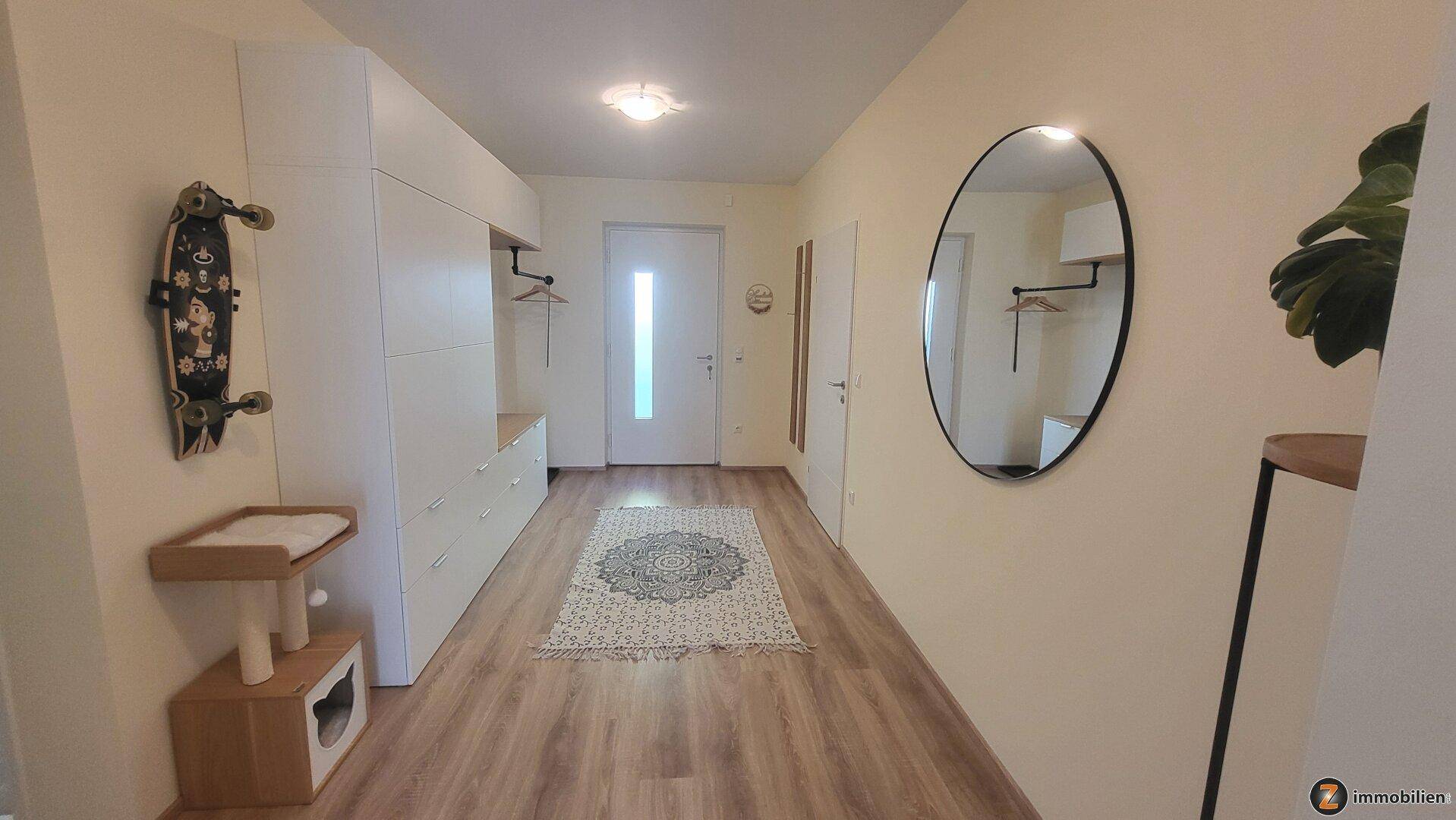 Heller Eingangsbereich mit modernem Garderobenschrank, Spiegel und Holzoptikboden.