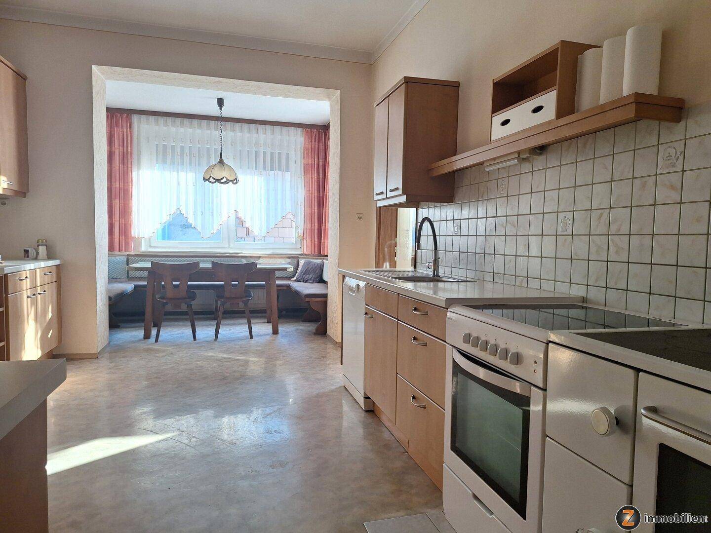 Helle Wohnküche mit Essbereich in einer Nische, ausgestattet mit einer Sitzbank und Esstisch.