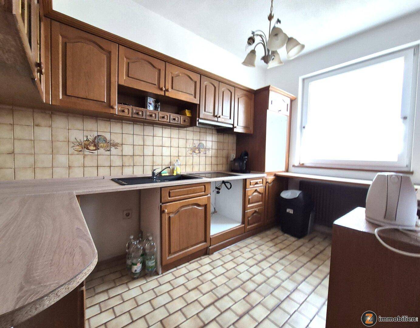 Traditionelle Küche mit Holzschränken, gefliestem Spritzschutz und einem Fenster.