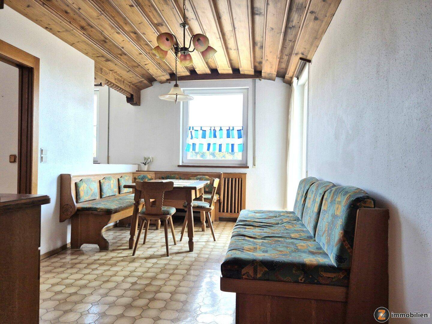 Wohn- und Essbereich mit Holzbalkendecke, traditionellen Möbeln und Fliesenboden.