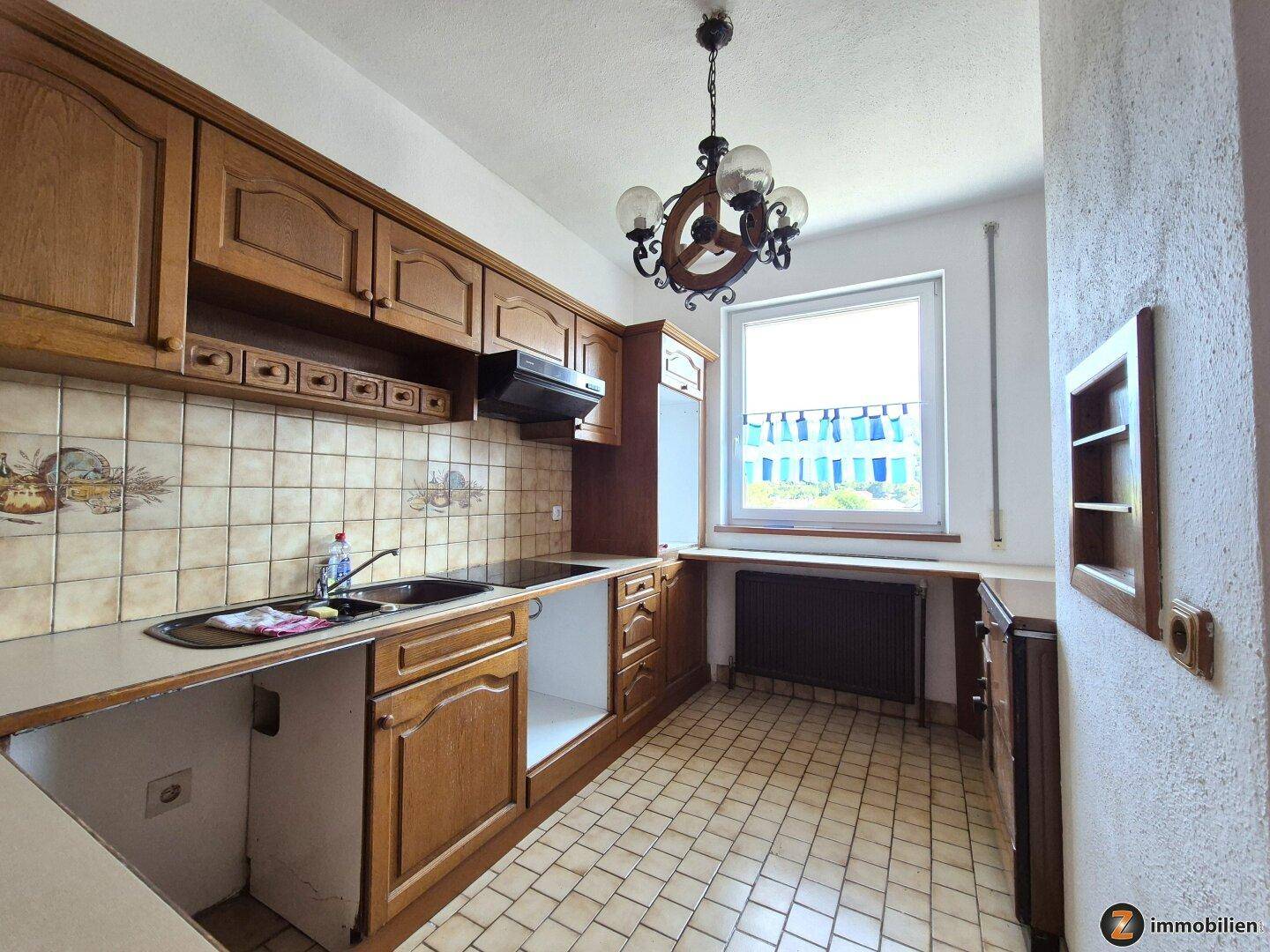Traditionelle Küche mit Holzschränken, gefliestem Spritzschutz und einem Fenster.