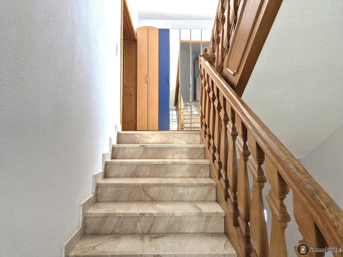 Treppenhaus mit Marmorstufen und einem Holzgeländer, das die oberen Etagen verbindet.