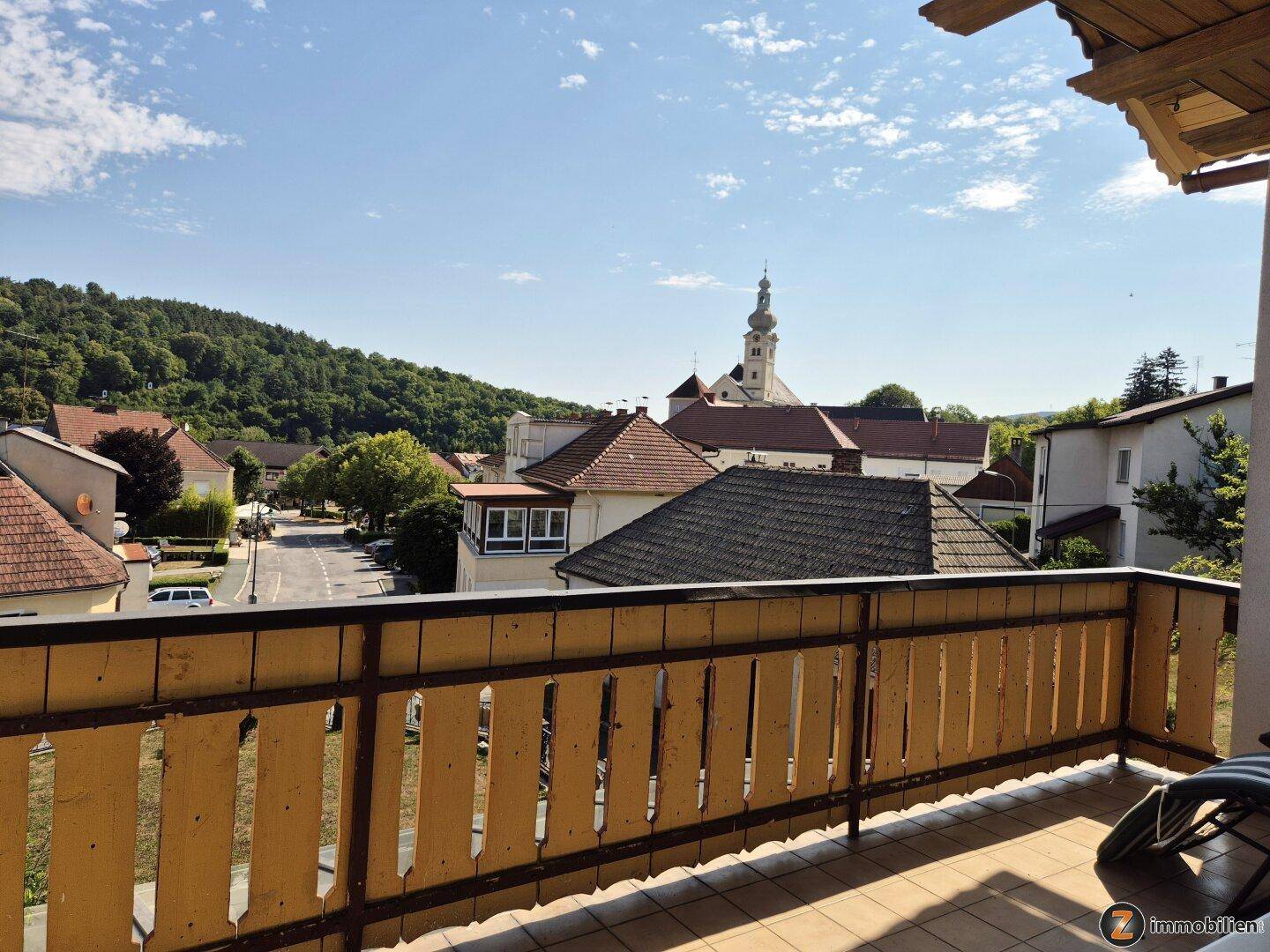 Geräumiger Balkon mit Fliesenboden und einem weiten Blick über die Stadt und grüne Hügel.