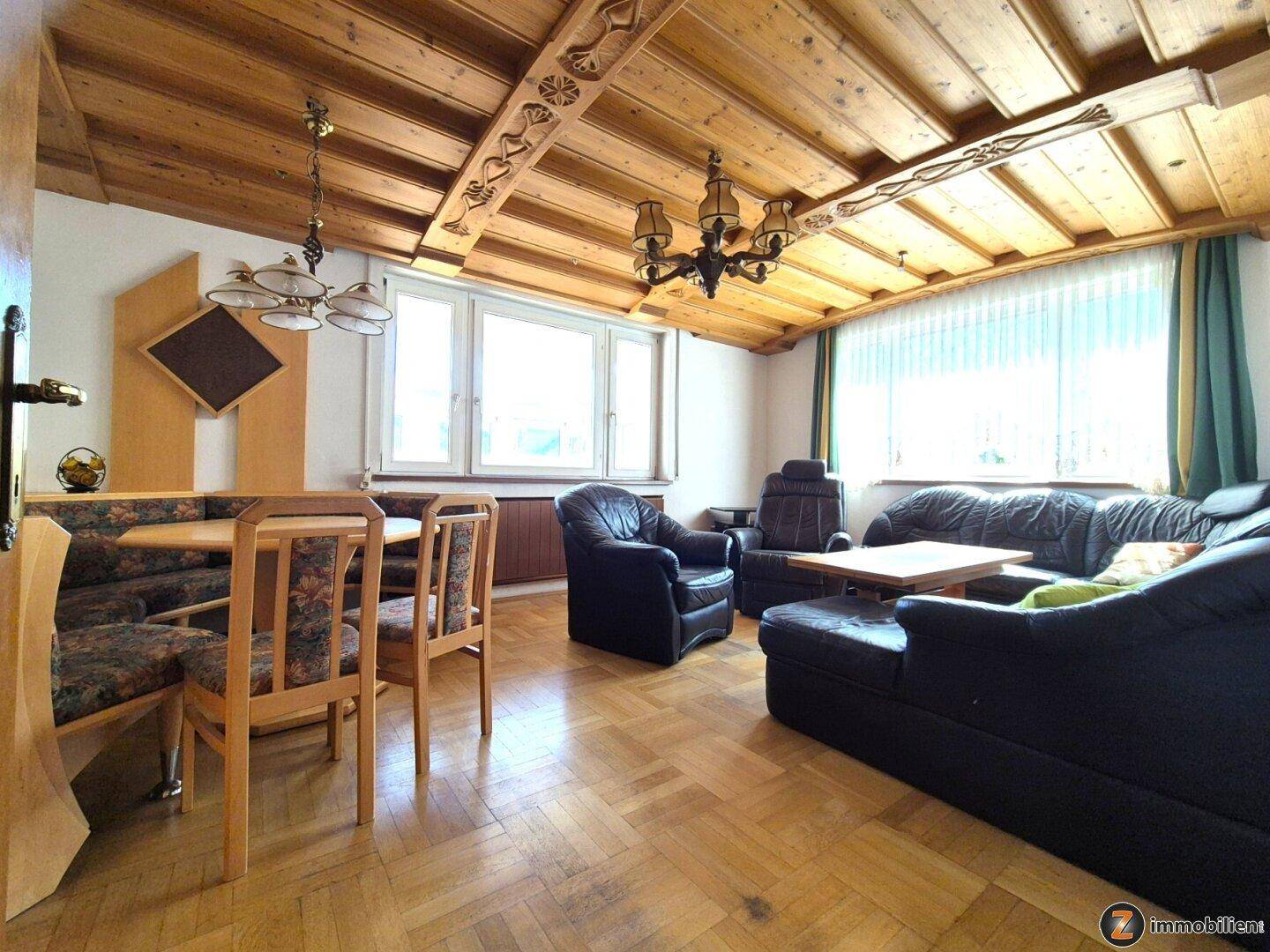 Gemütliches Wohnzimmer mit Holzbalkendecke, Parkettboden und traditionellen Möbeln.