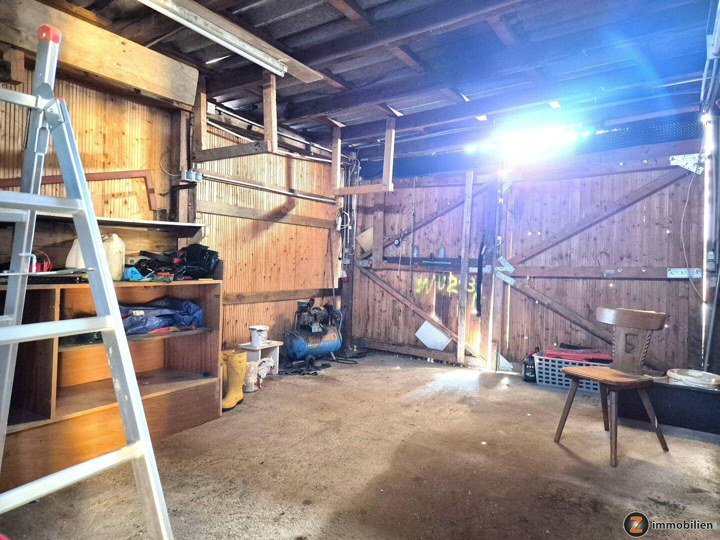 Rustikaler Werkstatt- oder Lagerraum mit Holzverkleidung, Leiter und verschiedenen Werkzeugen und Geräten.