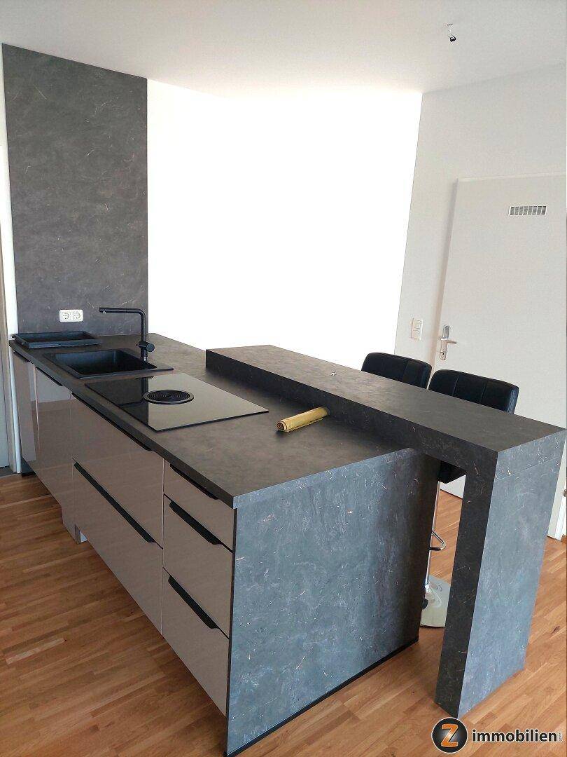 Detailansicht der modernen Kücheninsel mit Spüle, Induktionskochfeld und Frühstücksbar.