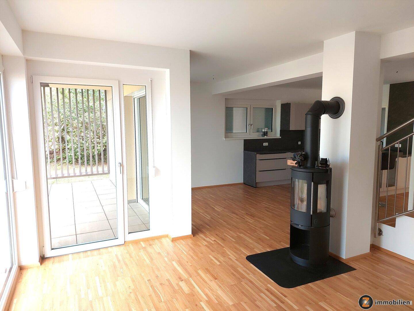 Geräumiges Wohnzimmer mit Holzofen, Parkettboden und direktem Zugang zur Außenterrasse.
