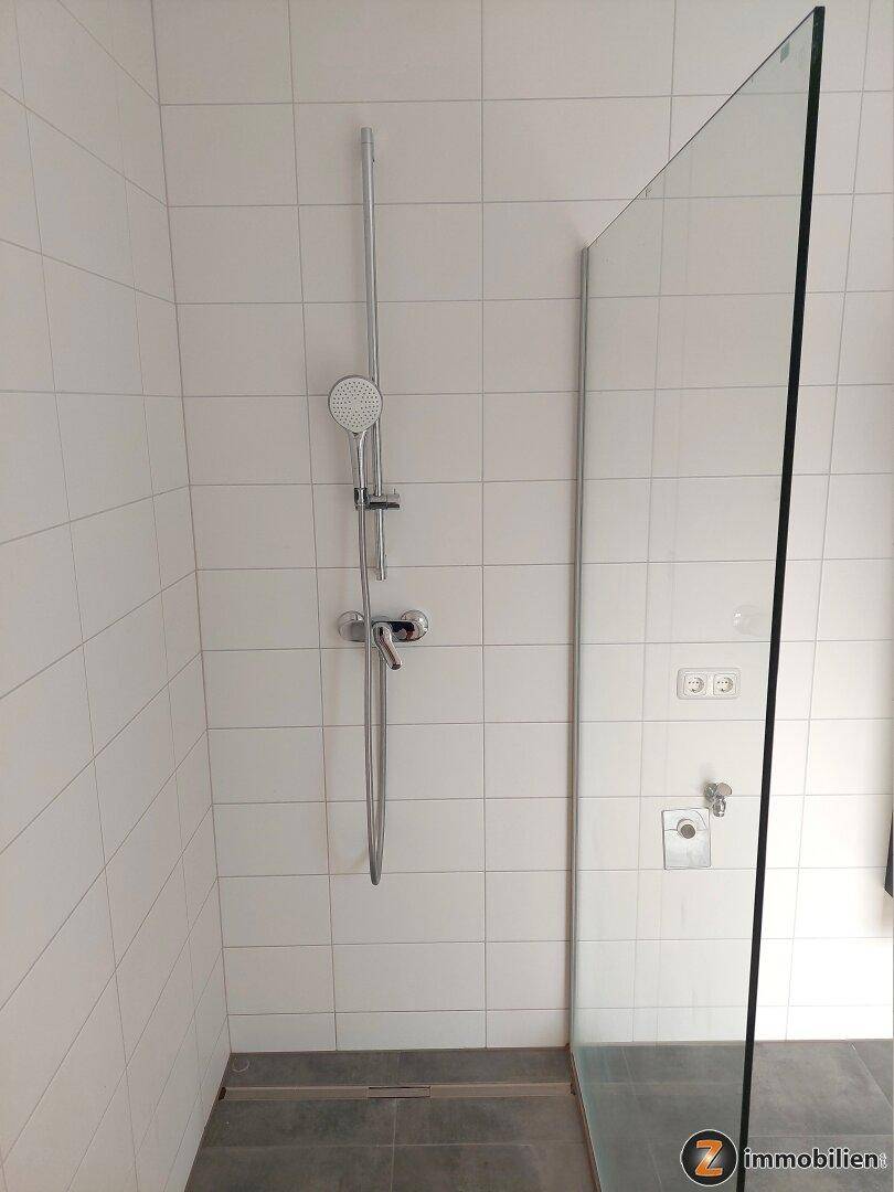 Geräumige, ebenerdige Dusche mit Glasabtrennung und modernen Armaturen.