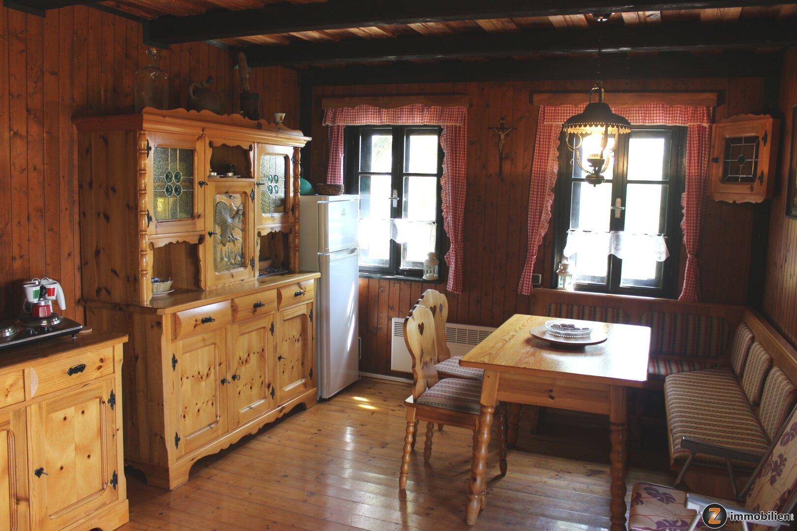 Gemütlicher Essbereich mit Holztisch, Eckbank und traditionellem Holzschrank in der Küche.