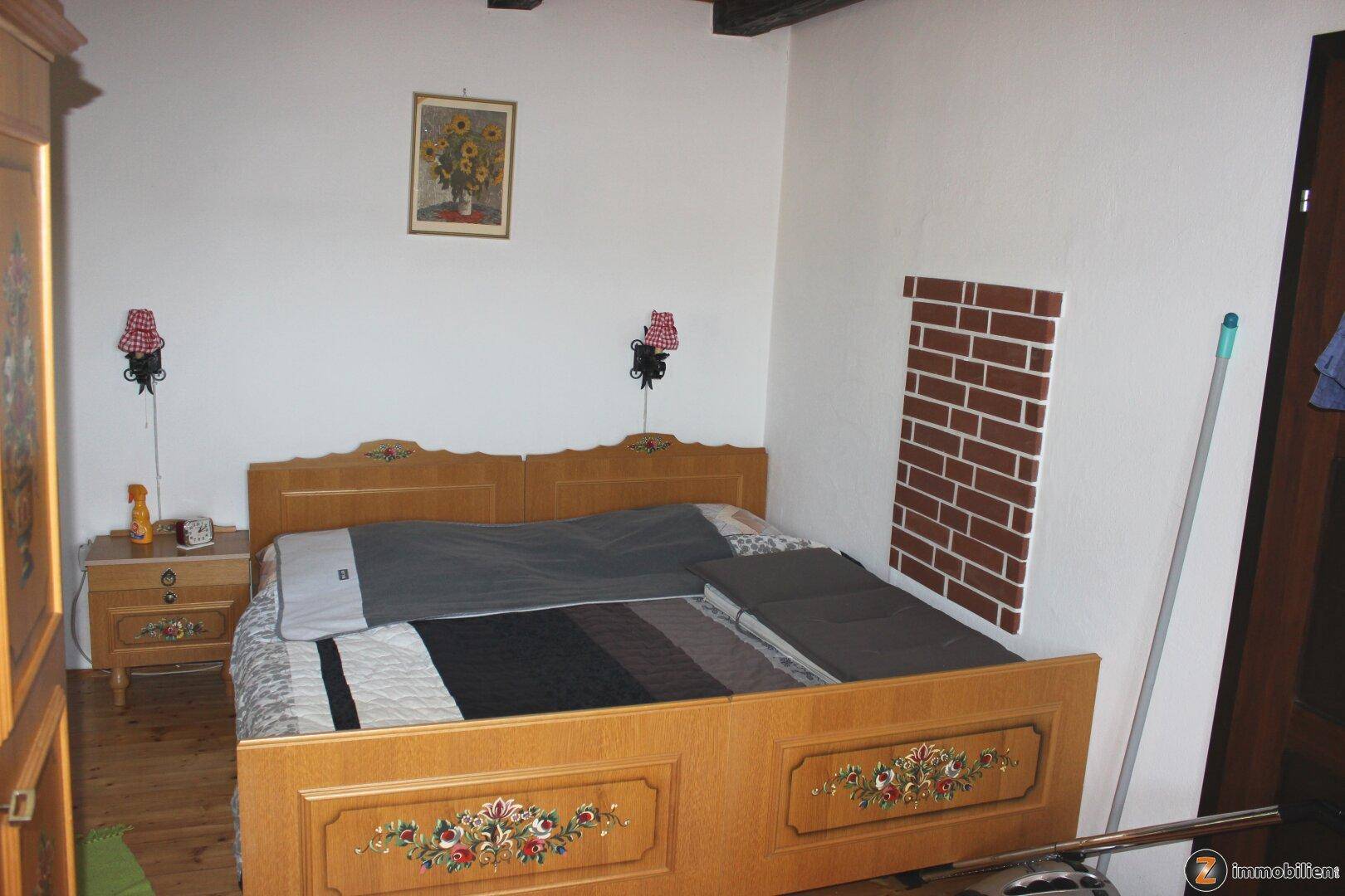Schlafzimmer mit traditionellem Holzbett, Nachttischen und schlichter, gemütlicher Einrichtung.