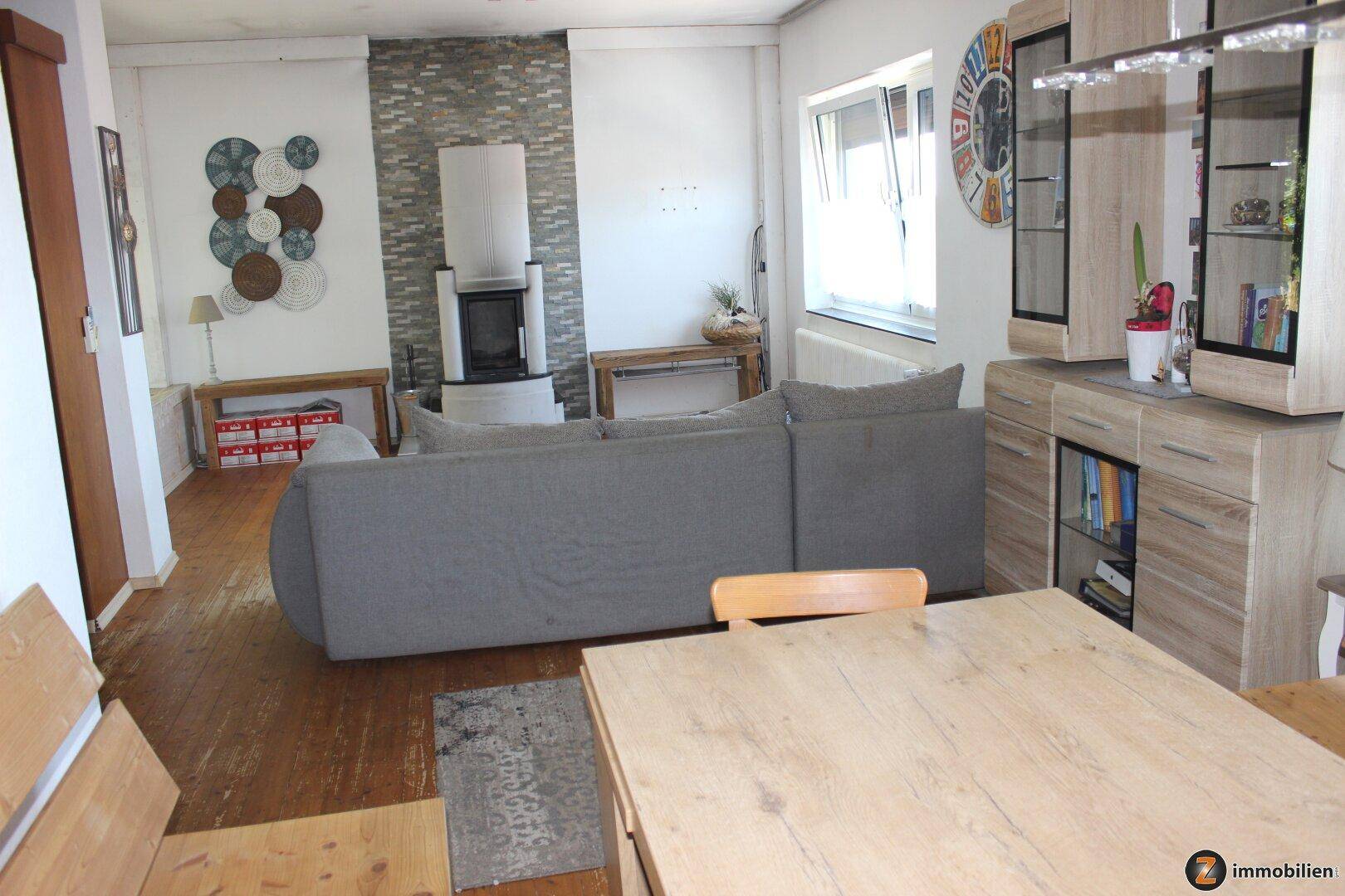 Heller Wohnbereich mit modernem Kaminofen, Holzboden und Essbereich.