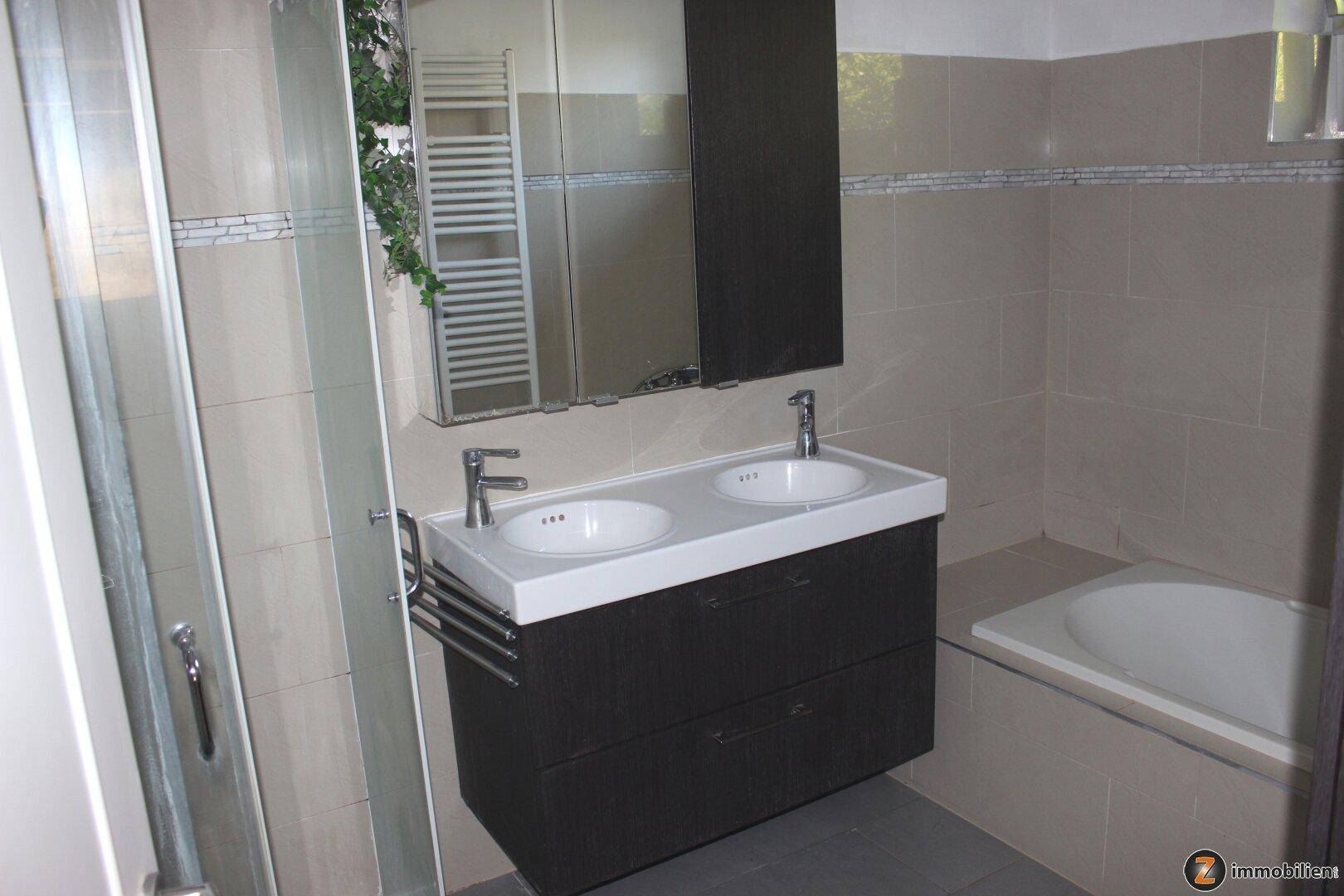 Modernes Badezimmer mit Doppelwaschbecken, Badewanne und separater Dusche.