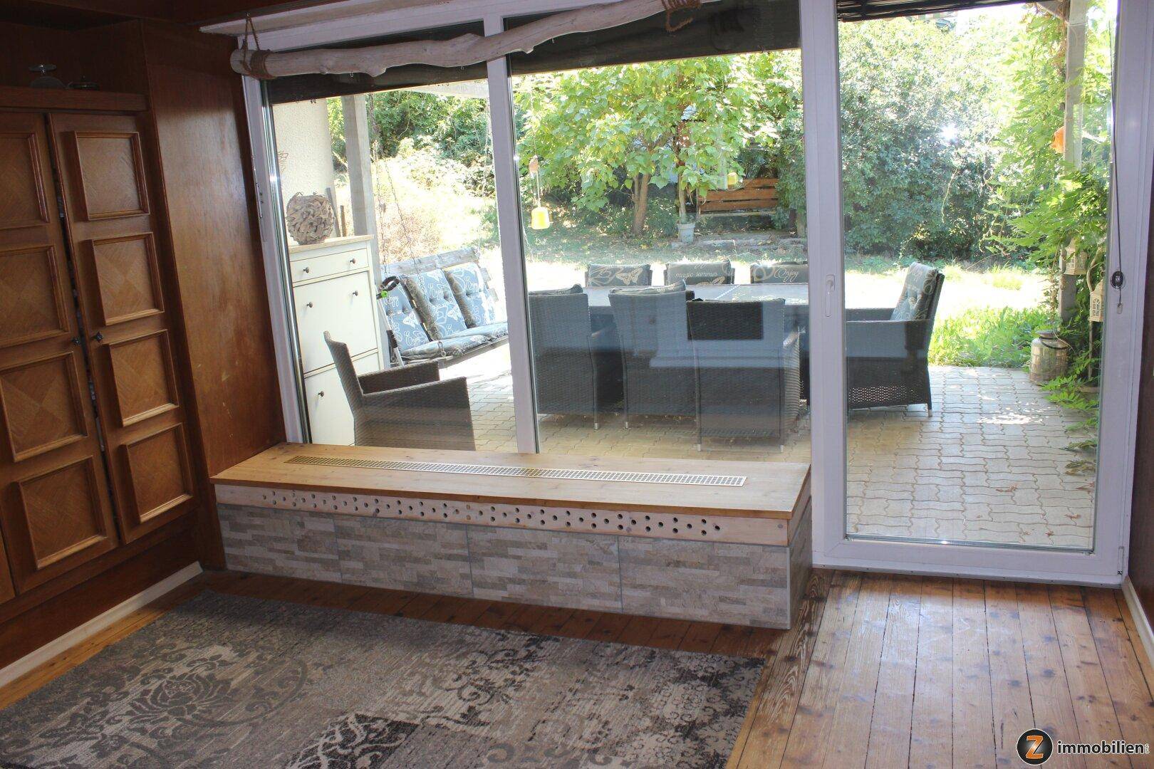 Wohnzimmer mit großen Glasschiebetüren und direktem Zugang zur möblierten Terrasse.