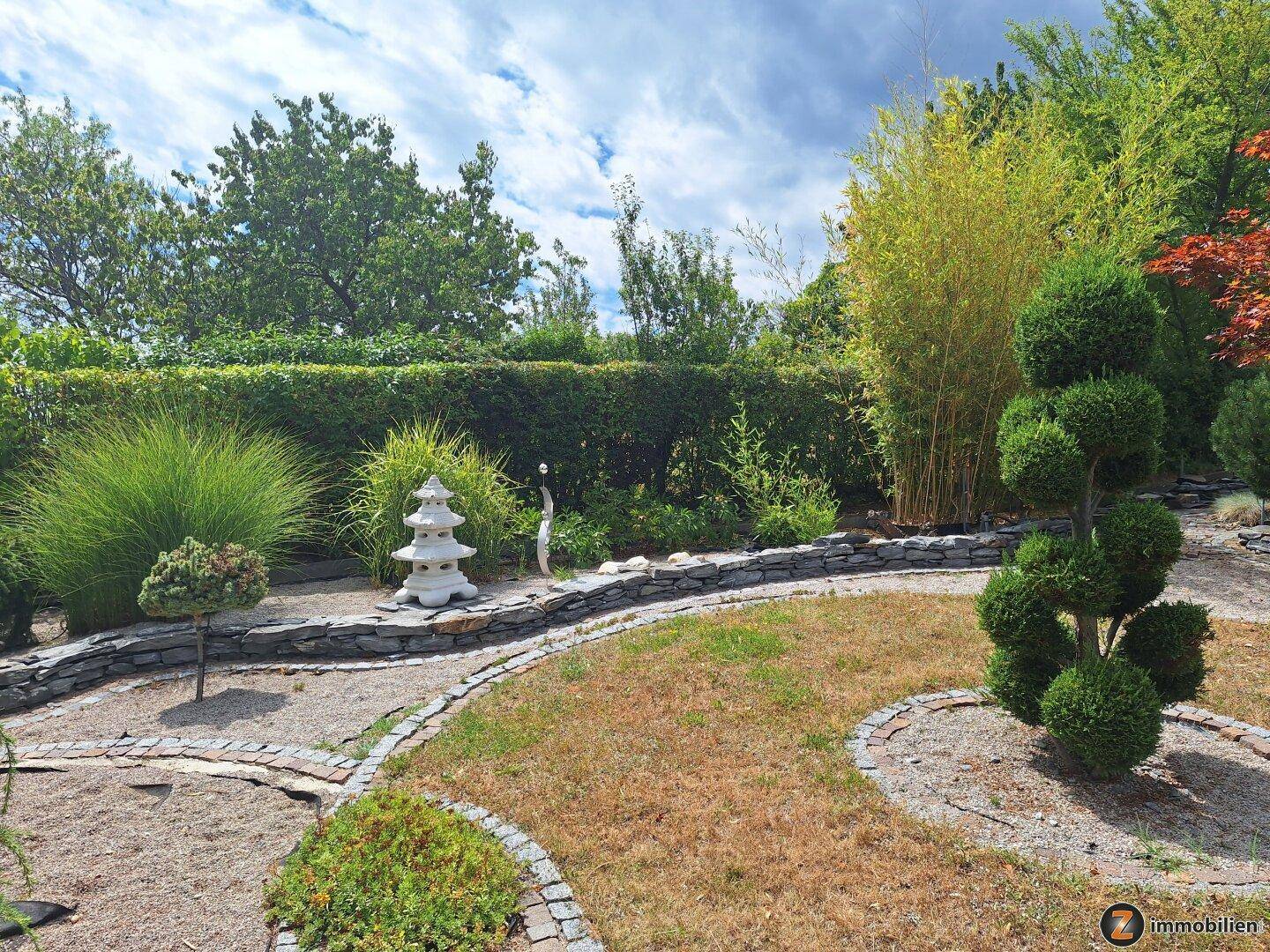 Gepflegter Garten mit Rasenfläche, Hecken und dekorativen Pflanzenarrangements.