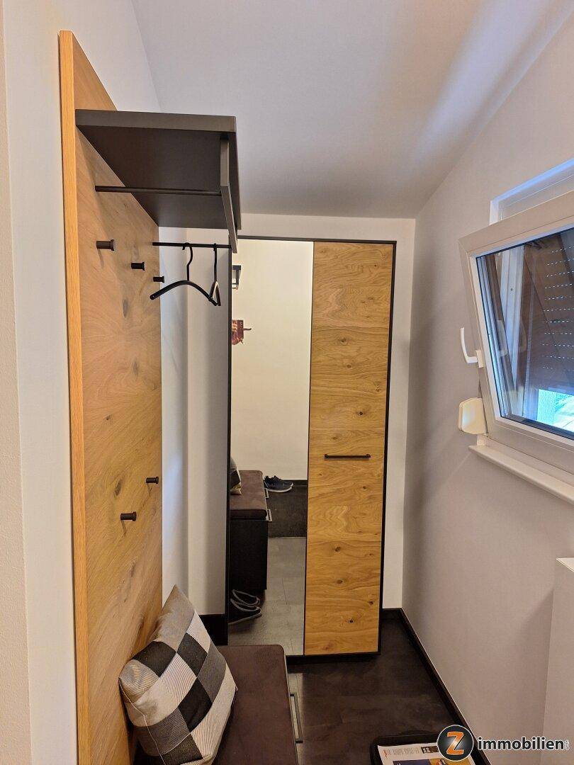 Heller Flur mit Garderobe, Spiegel und Fenster, das Tageslicht hereinlässt.