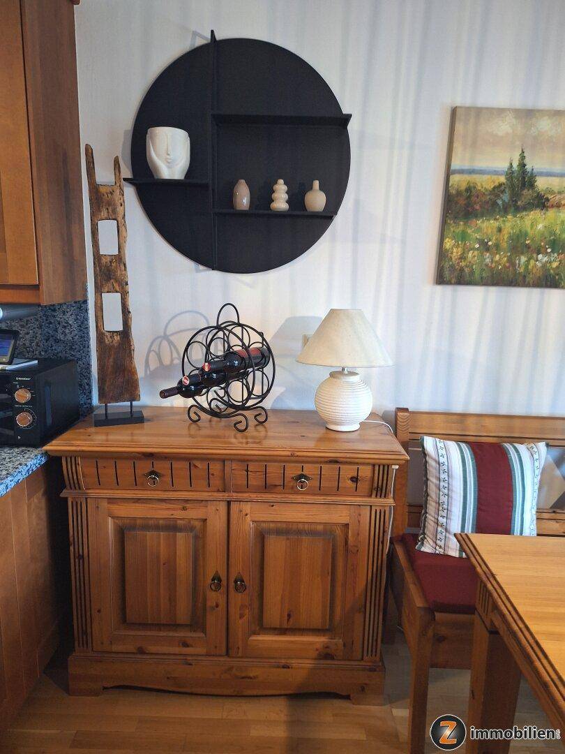 Detailansicht des Essbereichs mit rustikalem Holzschrank, Weinflaschenhalter und Tischlampe.