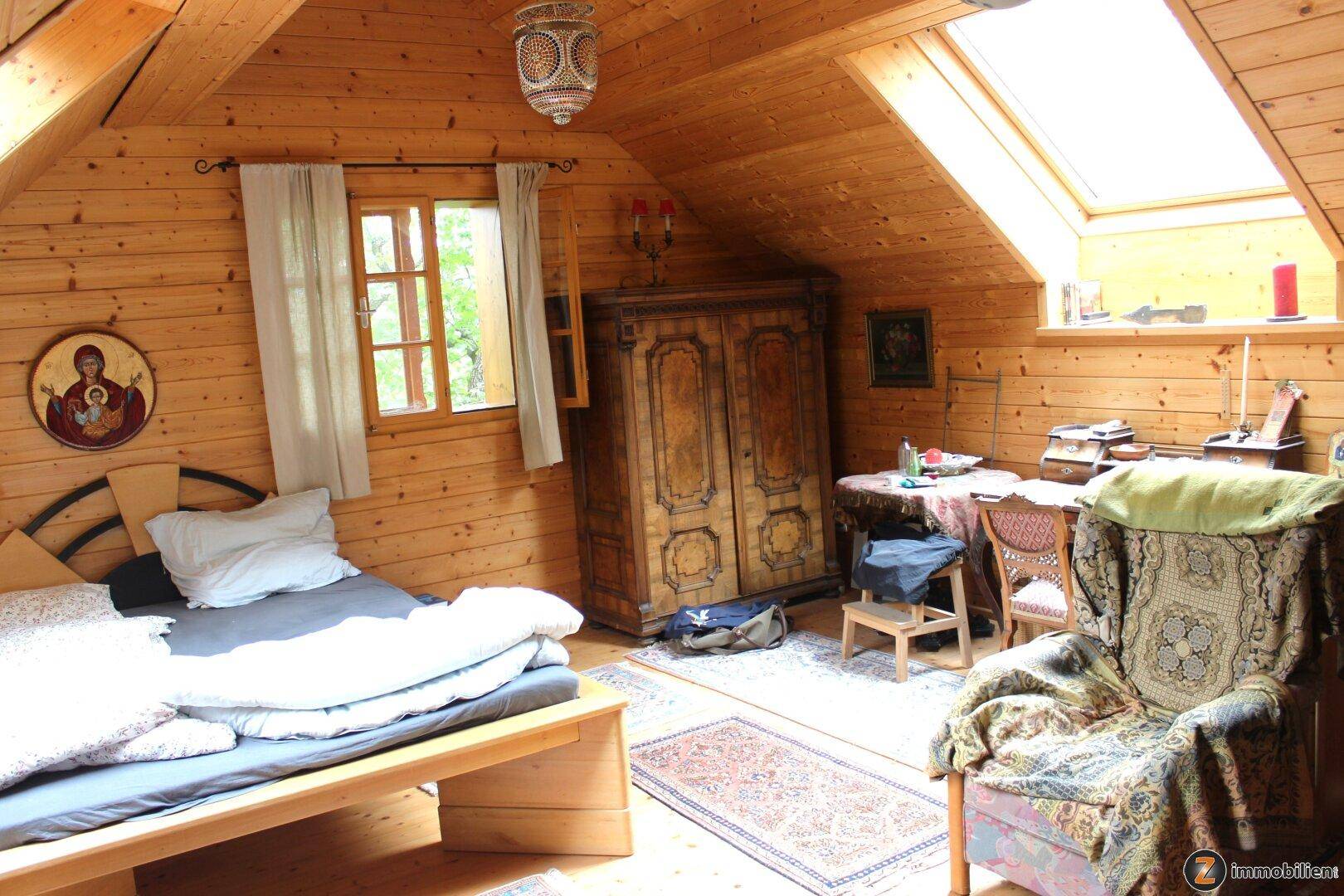 Schlafzimmer im Dachgeschoss mit Holzverkleidung, Dachfenster und rustikalen Möbeln.