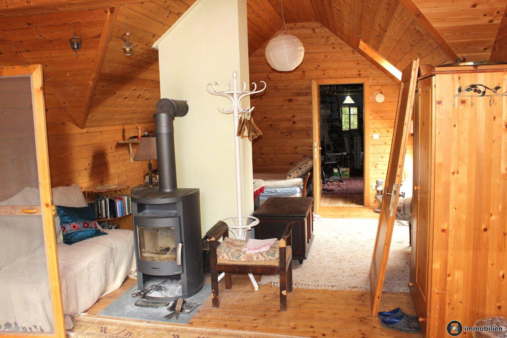 Offener Wohnbereich im Dachgeschoss mit Holzverkleidung, Kaminofen und rustikalem Charme.