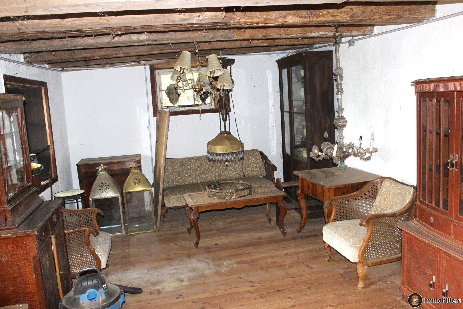 Rustikaler Wohnraum mit Holzbalkendecke, alten Möbeln und Kronleuchtern.
