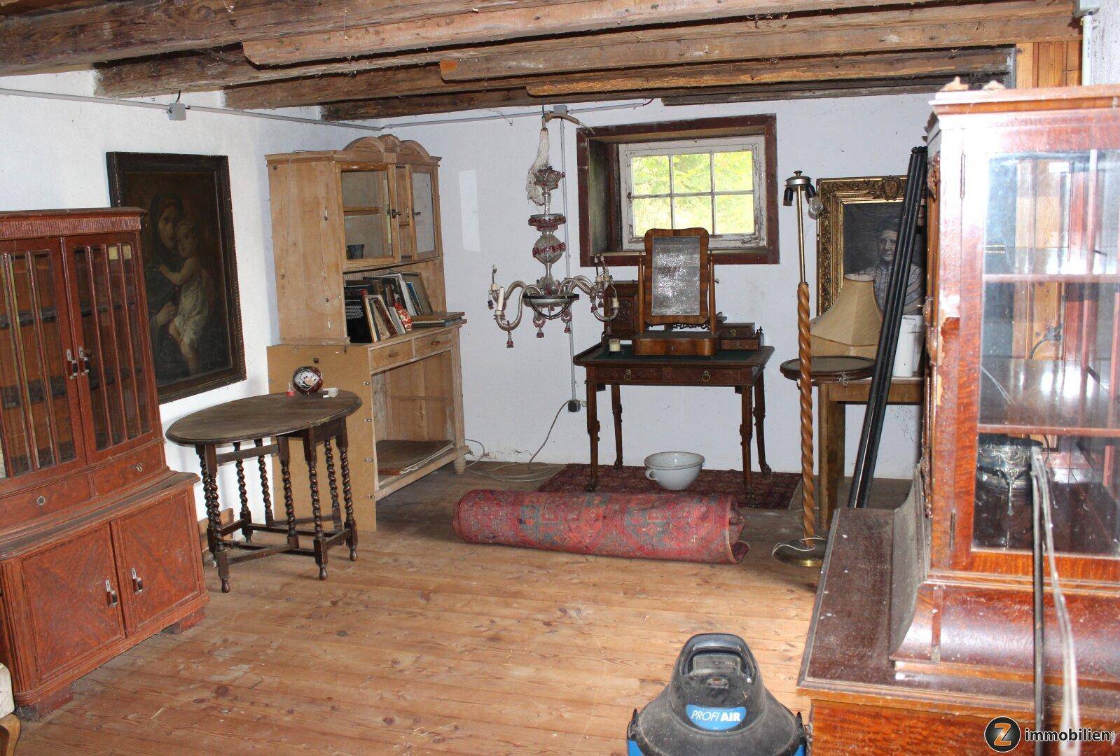 Geräumiger Wohnraum mit Holzbalkendecke, antiken Möbeln und Teppichen.