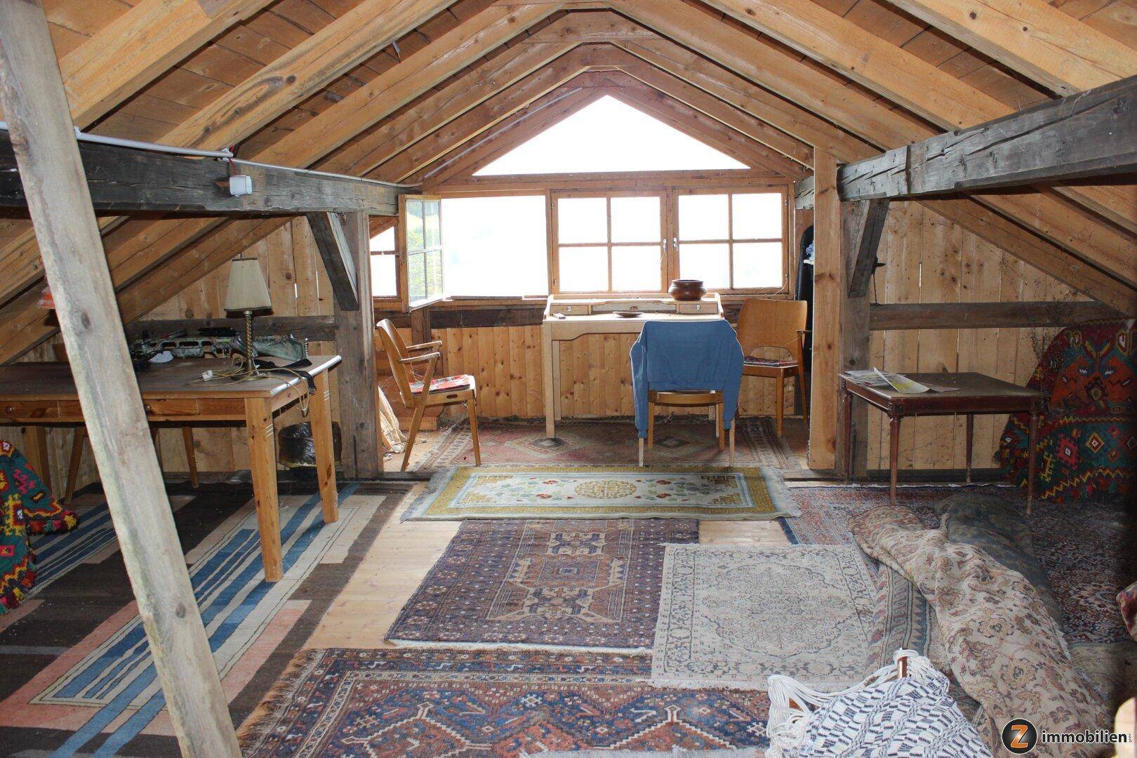 Ausgebauter Dachboden mit Holzverkleidung, Dachfenstern und Teppichen.