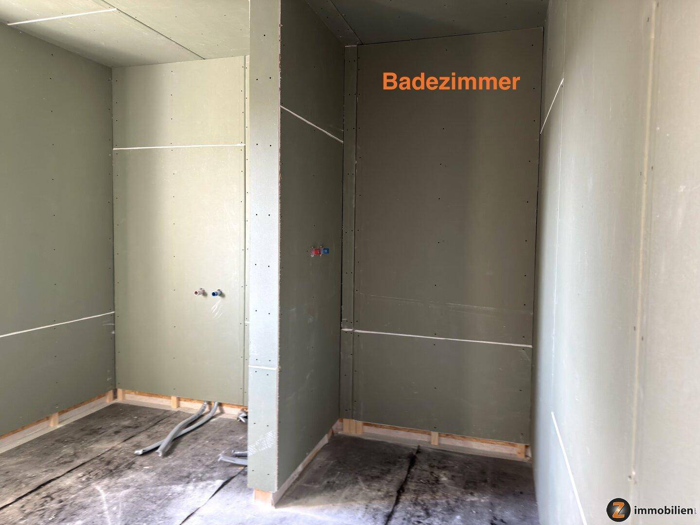 Badezimmer im Rohbau mit feuchtigkeitsresistenten Wänden und vorbereiteten Anschlüssen für Sanitäranlagen.