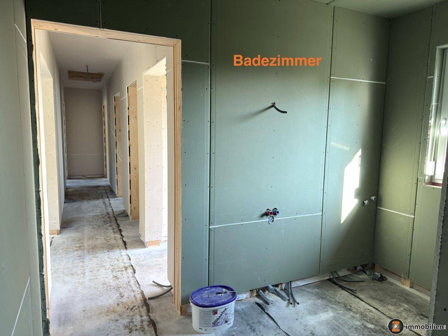 Geräumiges Badezimmer im Rohbau mit vorbereiteten Anschlüssen und Zugang zum Flur.