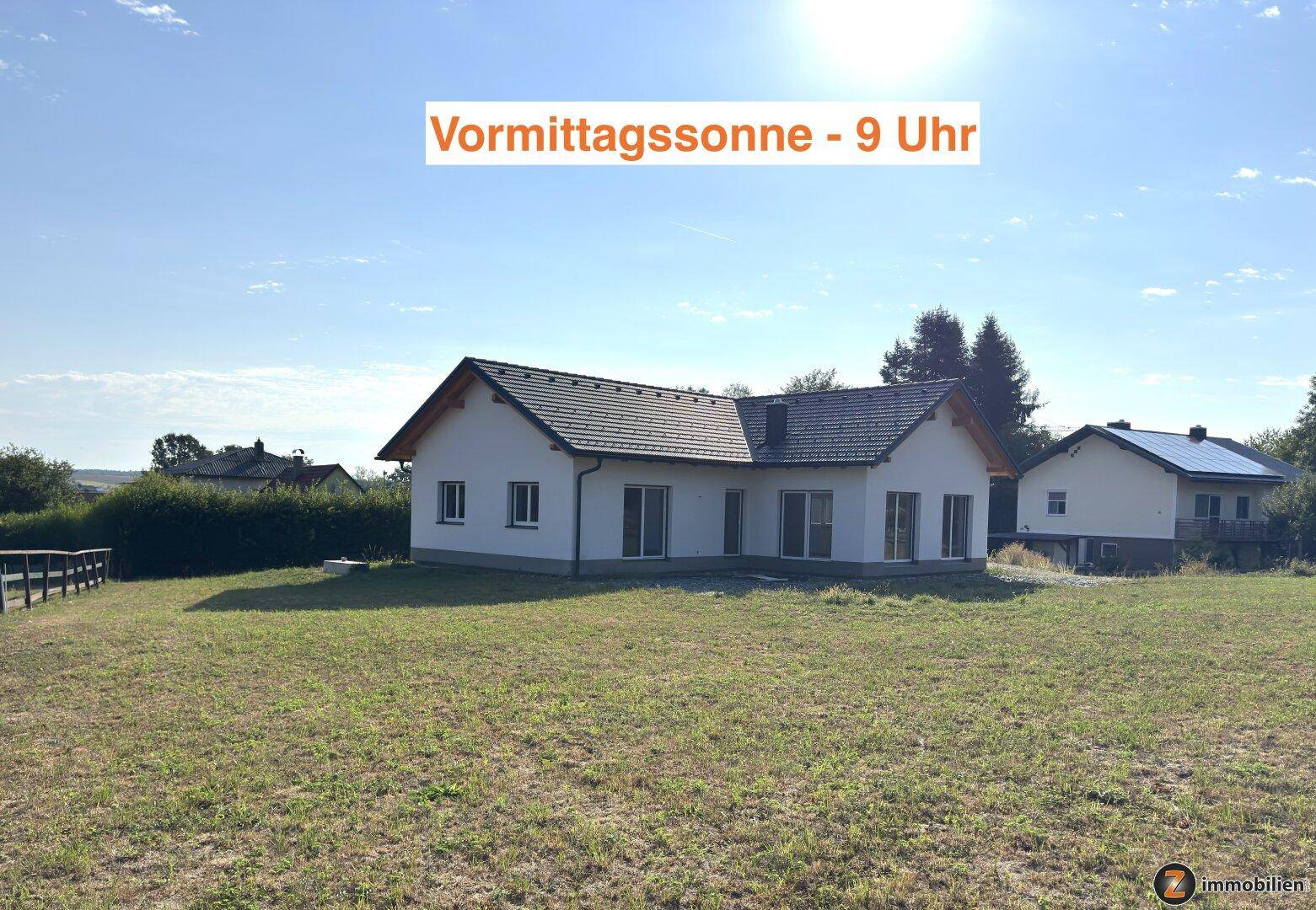 Neubau-Einfamilienhaus in der Vormittagssonne um 9 Uhr, umgeben von viel Grün.