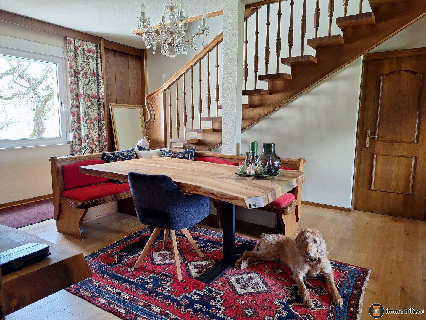 Gemütlicher Essbereich mit Holztisch, Sitzbank und Treppe zum Obergeschoss.