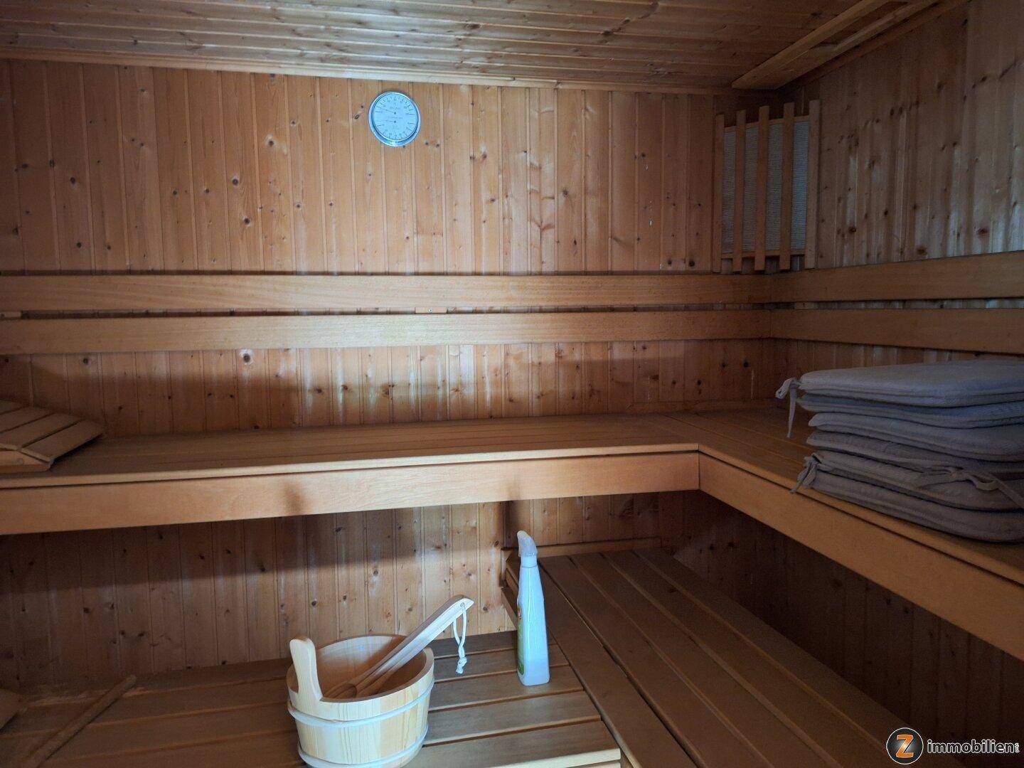 Gemütliche Holzsauna mit Bänken und traditionellem Zubehör für Entspannung.