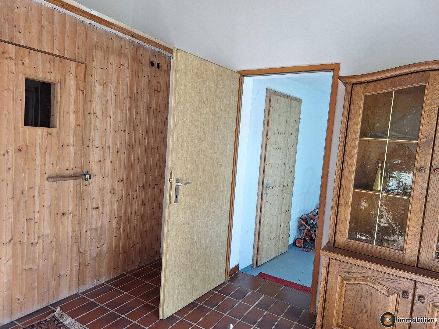 Eingangsbereich mit Holzvertäfelung, Fliesenboden und einem traditionellen Holzschrank.