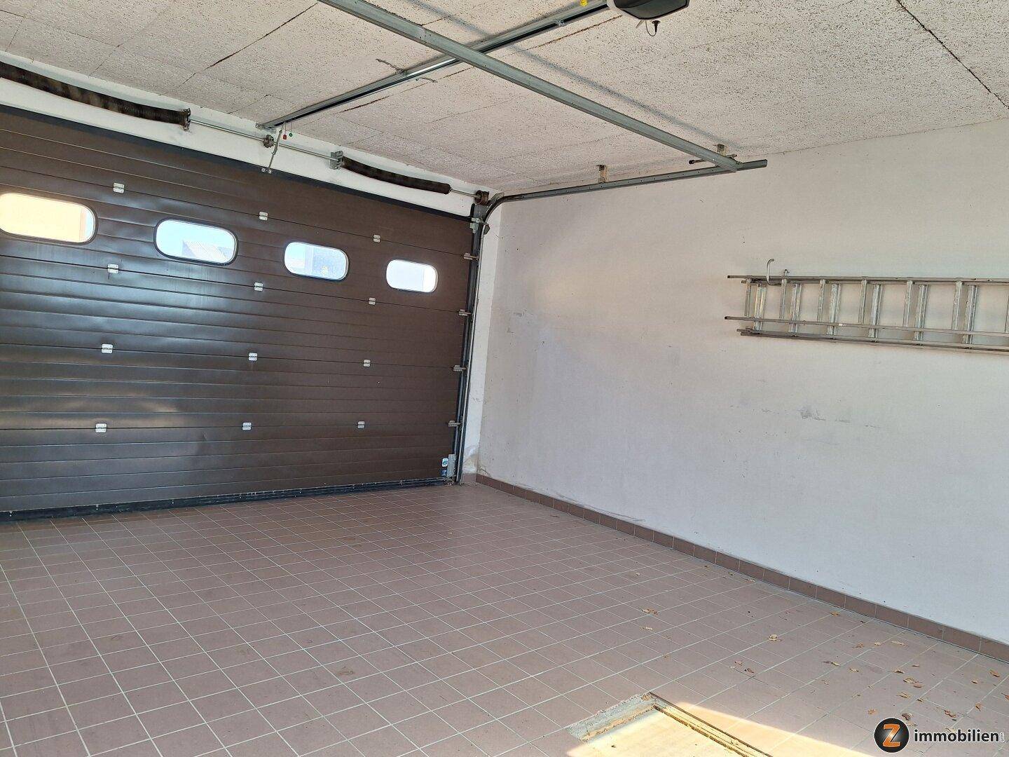 Geräumige Garage mit Fliesenboden und automatischem Sektionaltor.