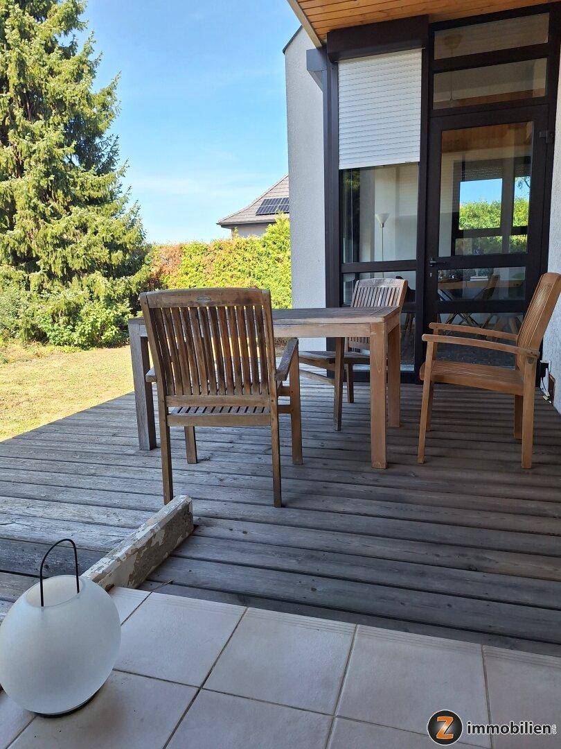 Holzterrasse mit Gartenmöbeln und Blick auf den grünen Gartenbereich.
