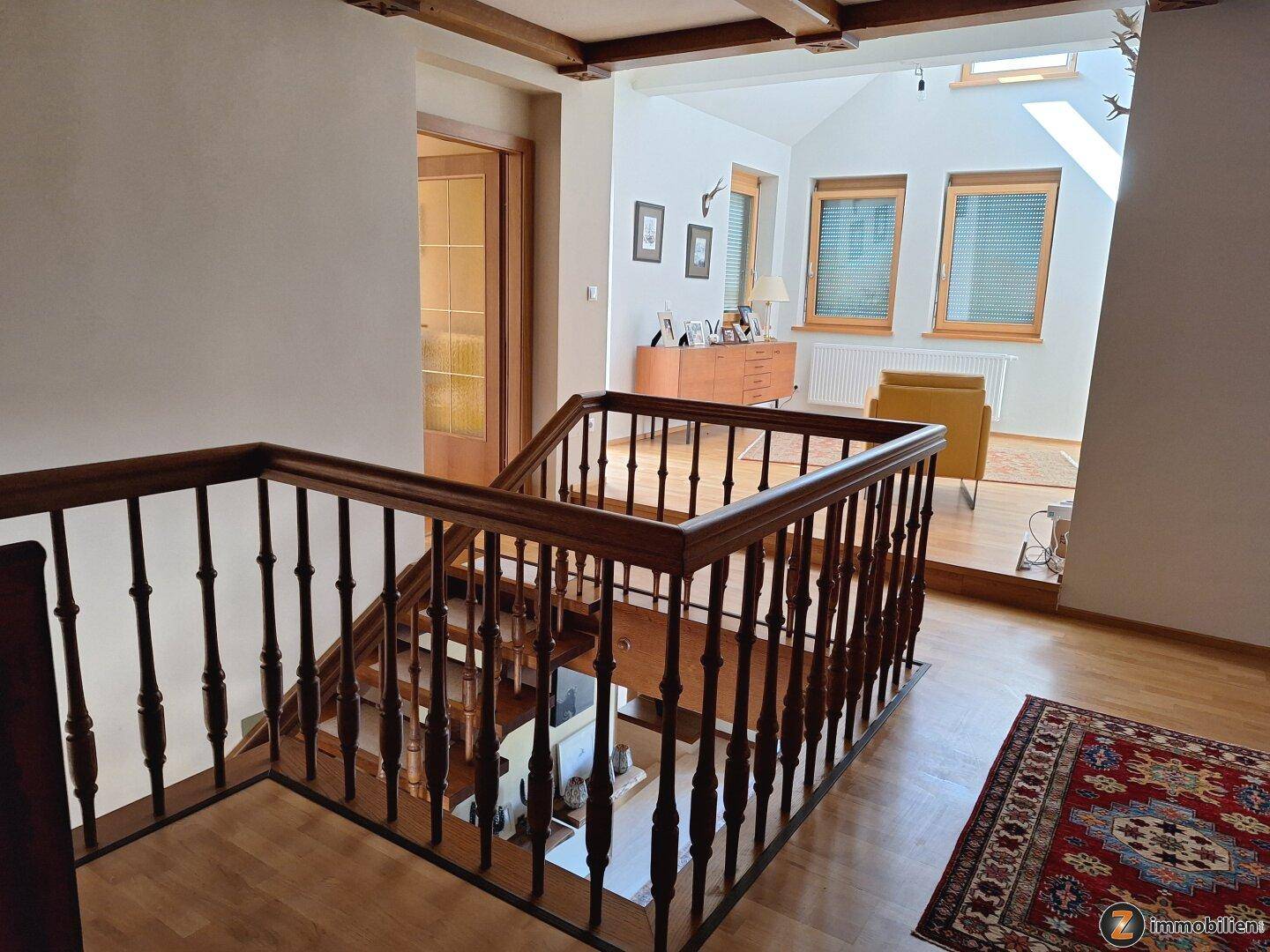 Geräumiger Flur mit Holztreppe, Galerie und Blick in den Wohnbereich.