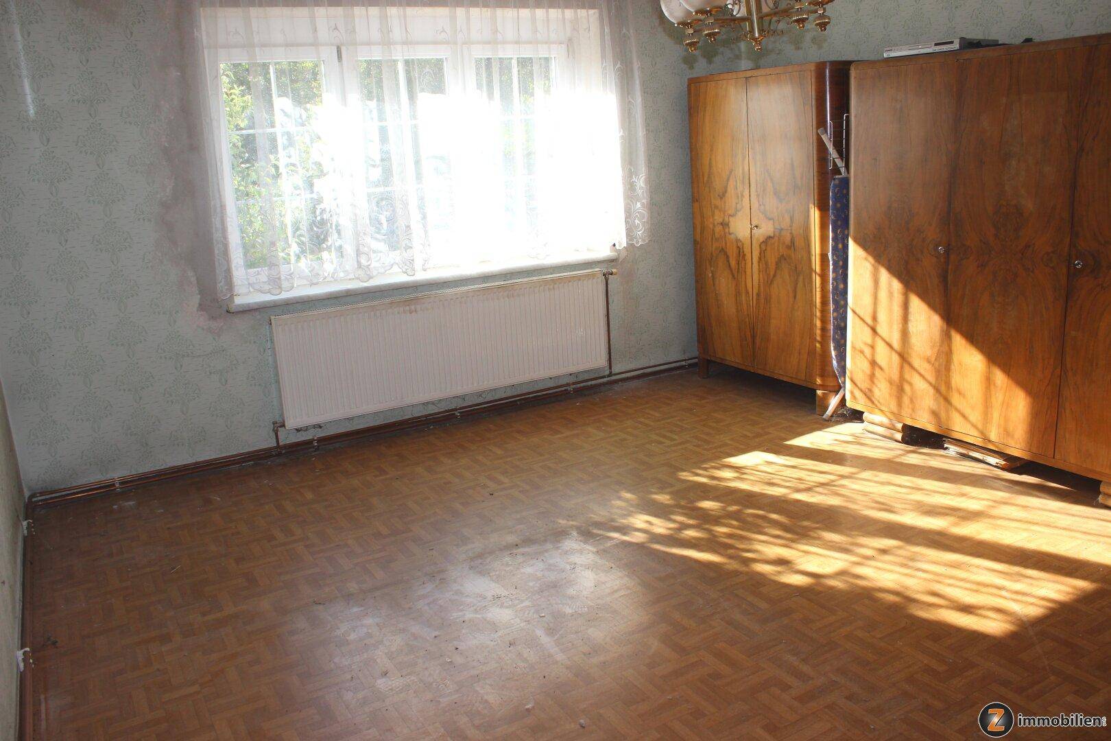 Helles Schlafzimmer mit Holzschränken, großem Fenster und viel natürlichem Licht.